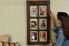 woman hangs picture frame on wall