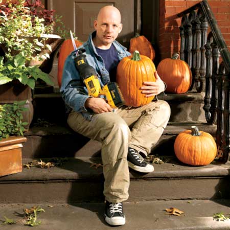 This Old House Editor, Scott Omelianuk with a reciprocating saw and some pumpkins sitting outside his front stoop