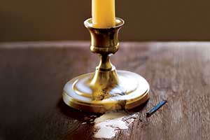 lit candle with wax dripping on the wood table