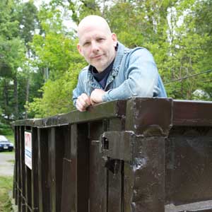 this old house editor scott omelianuk standing in a trash dumpster