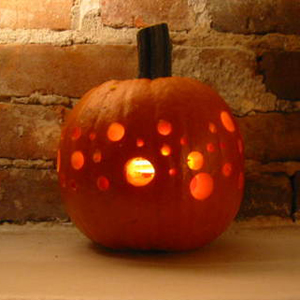 a pumpkin with holes in varying sized drilled into it, creating a disco ball effect