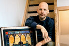 Scott Omelianuk on a stairway leaning on a salvaged stained glass window