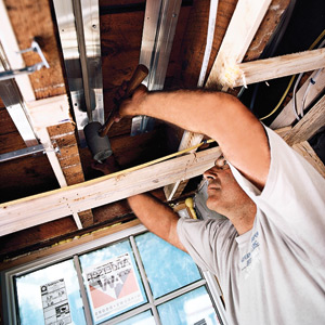 Perry uses a rubber mallet to tap the PEX into the aluminum track