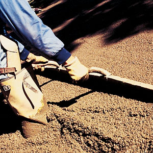 A screed (in this case, an aluminum bar with handles) is used to distribute and level the concrete. The surface is then worked with a float, which resembles a trowel, to make it smooth and to release any excess water that has risen to the top of the pour. Installers must be careful not to overwork the concrete, as releasing or bleeding too much water leaves a chalky surface and compromises the strength of the slab. 
