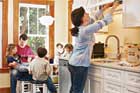 mother searching in kitchen cabinet while family in background