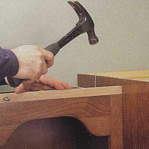 nail wood strips along the tops of the cabinets 