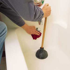 Photo 3: HOLD A wet rag over the drain holes in the overflow plate to prevent the pressure built up by plunging from escaping. 