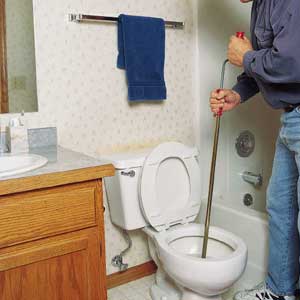 TURN THE crank and push down simultaneously to force the auger cable through the tight curves of the toilet trap.