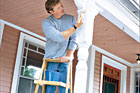 Toh host Kevin O'Conner on a step ladder painting the porch