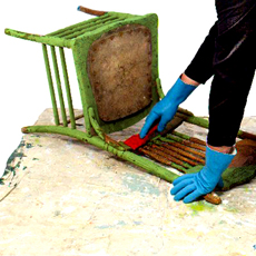 someone scraping old paint from a vintage chair