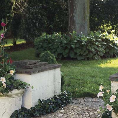 pea gravel leads to an oval of decorative hardscape flanked by short stucco pillars in Pennsylvania garden