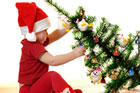 child pulling down a fully decorated christmas tree