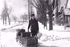 milkman with milk cart standing on snowy residential street