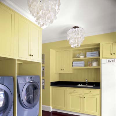two chandeliers hanging in a yellow painted laundry room