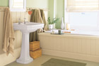 upgraded bathroom with sea foam colored walls, towel racks, pedestal sink and paneled tub