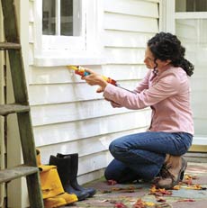 woman caulking window for energy efficiency