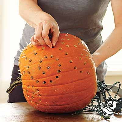 drilling designs into pumpkins nad lighting them with strings of christmas lights