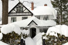 house and trees burdened by extreme snow fall