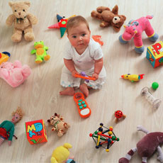 baby sitting on floor surrounded by toys