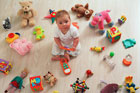 baby sitting on floor surrounded by toys