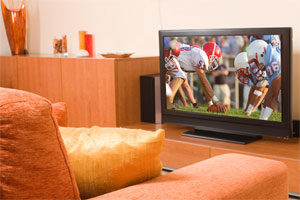 large screen tv playing a football game in from of a comfy chair