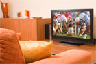 large screen tv playing a football game in from of a comfy chair