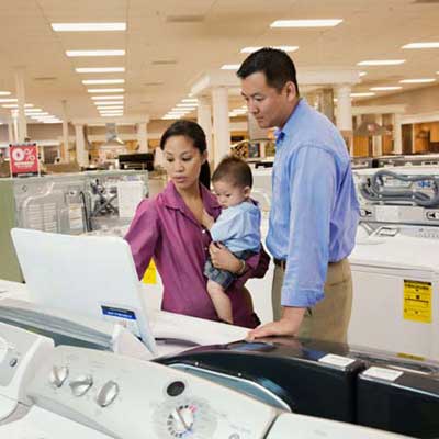 two adults and an infant shopping in an appliance showroom