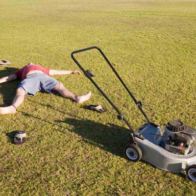 man lying next to lawn mower in yard