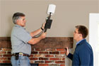 tom silva and homeowner looking at wall sconce for use as efficient lighting