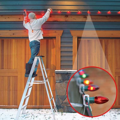 Man hanging christmas lights above garage
