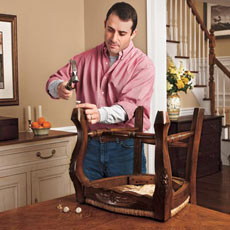 man attaching tacks with felt pads to bottom of chair legs
