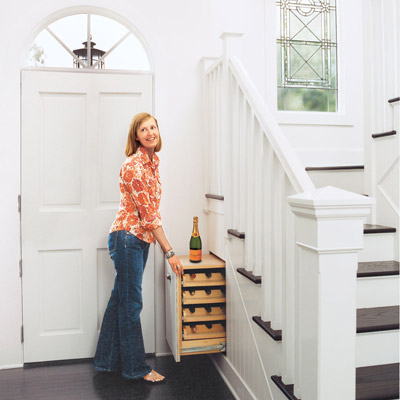 woman pulling out an under the stairs wine rack in her foyer