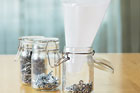 using wax paper to funnel small nuts into a mason jar