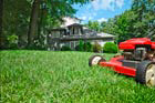 green healthy yard and trees with push lawnmower and house