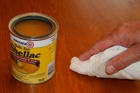 hand shown wiping shellac onto a wood surface with cheesecloth