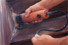 hands using a multi function detail sander in the corner of a stair riser