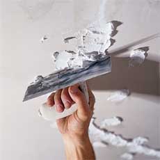 hand smoothing new plaster over repaired areas of a ceiling