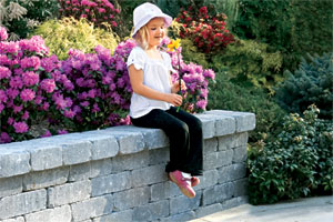 Little girl with flowers on sitting wall