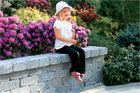Little girl with flowers on sitting wall