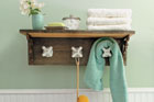 completed towel rack made from vintage taps with shelf installed in a green bathroom