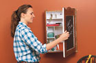 woman putting an envelope in the pocket of a message center made from a vintage medicine cabinet