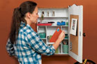 woman putting an envelope in the pocket of a message center made from a vintage medicine cabinet