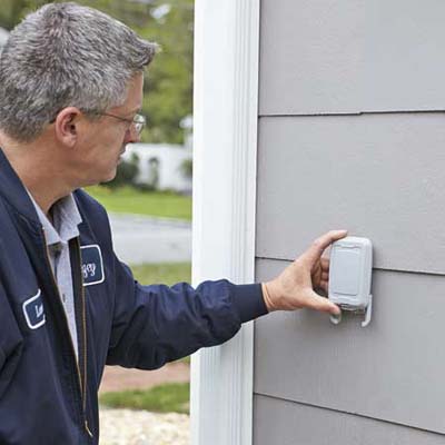 Lance Marques mounts the outdoor sensor that allows the thermostat to measure the temperature outside