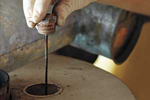 a latex-gloved hand lifts an anode rod that is way overdue for replacement from a water heater