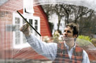 man wiping away a soapy window pane with a squeegee