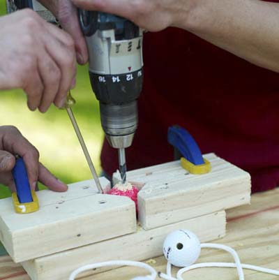 man drilling hole in golf ball for ladder golf game set