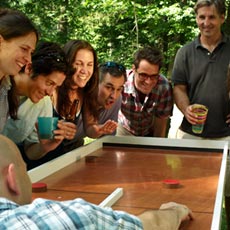 group of happy people standing around a team saturday ricochet game board