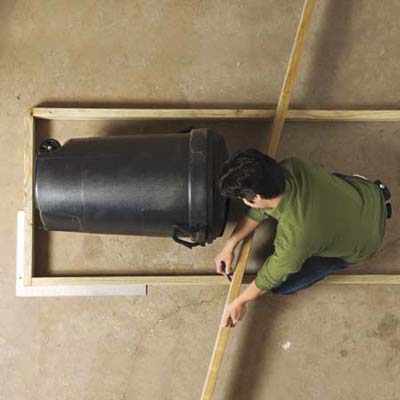 Mark Powers checking the size of his trash shed's framing using a 32-gallon trash can
