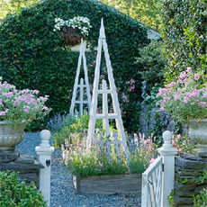 pyramid trellis installed in a beautiful yard filled with plants and flowers