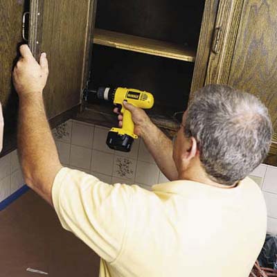 John Dee removing cabinet door with a cordless driver